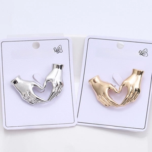 Detailed macro view of heart-shaped hands brooches in gold and silver metallic finishes