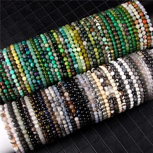 Detail of 8mm natural stone bead bracelets with engraved golden mantra on dark cylinders