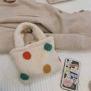 Detailed view of white plush tote bag with vibrant multi-colored polka dots on quilted surface