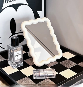 Macro detail of white wavy tabletop makeup mirror on a stylish checkered tray
