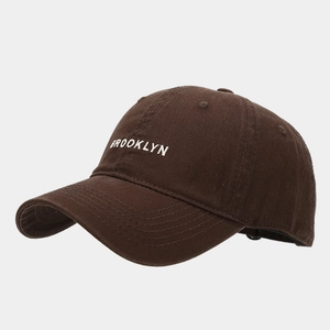 Detail shot of white Brooklyn embroidery on brown cotton baseball cap with twill texture