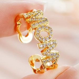 Close-up of golden MOM letter ring with micro-pave zircons and adjustable open band