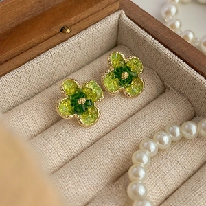 Vue macro de boucles d'oreilles fleurs vertes vintage avec bord doré et perles en boîte