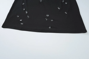 Détail d'une robe noire élégante ornée de cristaux en forme de gouttes d'eau