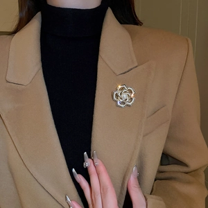 Détail de la broche fleur en perles et cristaux sur le revers d'un manteau en laine