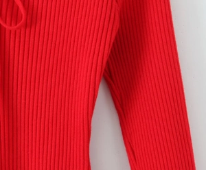 Detailed macro view of the bright red ribbed knit fabric and sleeve stitching detail