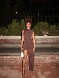 Detail of a brown slim fit ruched dress featuring an irregular long hem and elastic fabric