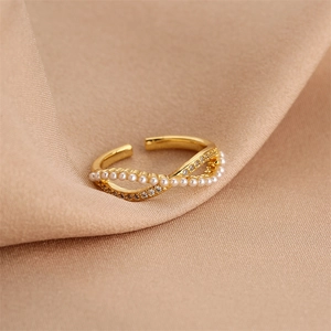 Macro shot of gold infinity ring with white pearls and sparkling zircons on beige silk