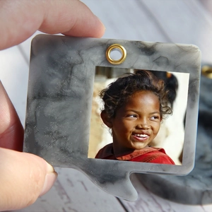 Close-up of speech bubble shaped resin frame with grey marble texture and gold eyelet