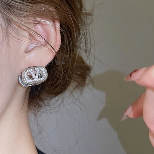 Close-up of a silver V-shaped earring with pavé-set zircons worn by a model
