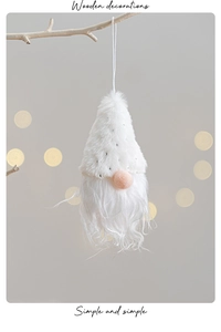 Close-up of white plush Christmas gnome hanging on a branch with bokeh light background