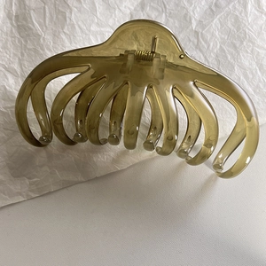 Macro detail of large olive green jelly hair claw clip with golden metal spring