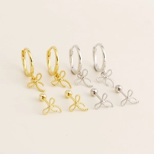Minimalist S925 silver bow earrings in gold and silver finishes on a beige background