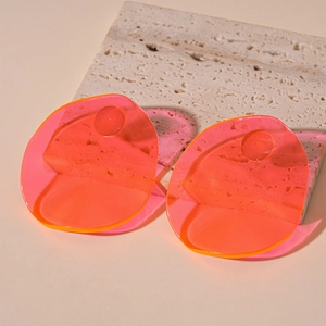 Detailed shot of oval translucent pink resin earrings on a travertine stone surface