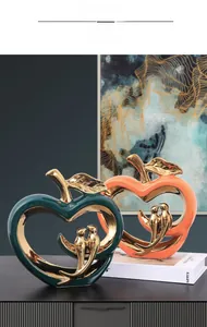 Detail van moderne keramische appelsculpturen met gouden vogels in groen en oranje