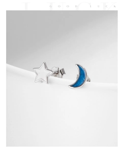 Macro shot of asymmetrical s925 silver stud earrings with blue moon and white star enamel