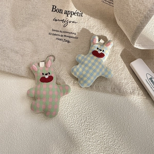 Detail of cute checkered fabric bunny charms with metal ball chains on a canvas bag