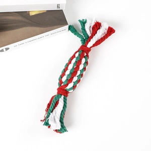 Macro shot of durable red, green, and white braided cotton rope dog chew toy with tassels