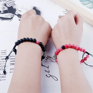 Close-up of magnetic heart charms connecting black and pink natural stone bead bracelets