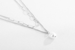 Detail of double-layered silver chain necklace with a baroque pearl pendant
