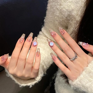 Detailed view of handmade press-on nails with blue gems, glitter, and pearls