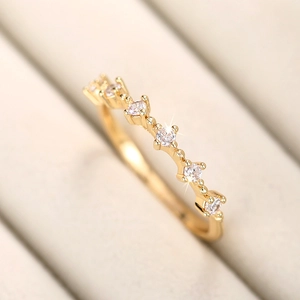 Primer plano detallado de un anillo de oro con circonitas onduladas sobre un soporte texturizado