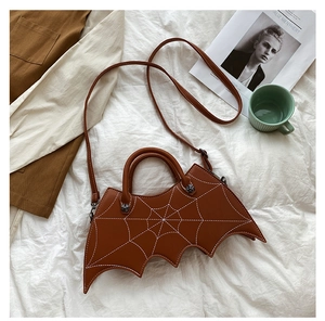 Brown bat-shaped PU leather bag with spider web embroidery on a cozy lifestyle setting