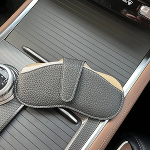 Portable dark grey leather eyewear pouch on car console showing sleek pebble grain texture