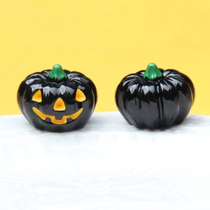 Detailed view of two small black Halloween pumpkins on a white textured plate