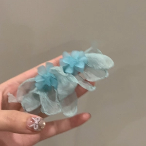 Detailed view of handmade blue fabric flower earrings with translucent petal texture