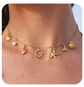 Detail of gold ocean-themed necklace featuring baroque pearls and shell charms on a model