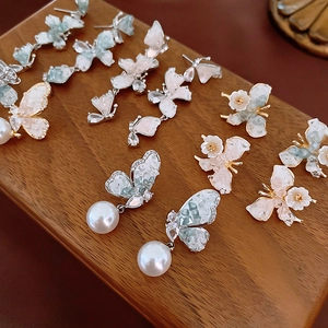 Detailed view of elegant gold butterfly earrings with pearls and crystals on wood