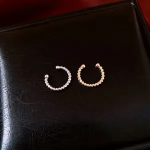Pair of elegant gold and silver plated twisted texture ear cuffs on black leather