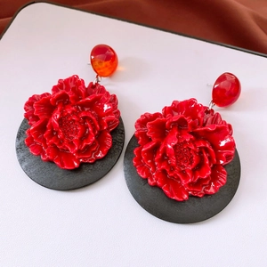 Detail of red flower pendant earrings with vintage resin petals and black circular base