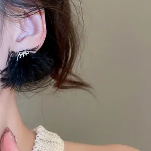 Eleganti orecchini con piume nere e dettagli in argento indossati da una modella