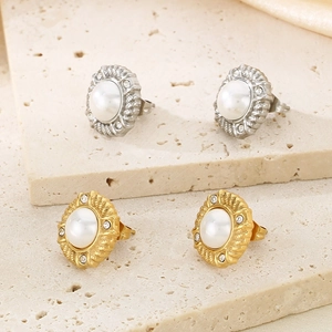 Detail view of gold and silver textured earrings featuring central pearl and zircon stones