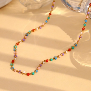 Close-up of a delicate 18K gold-plated chain with colorful beads in soft lighting