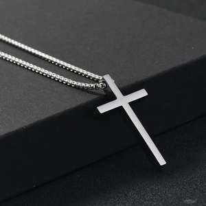 Detailed view of silver cross pendant with beaded chain on dark matte surface