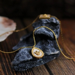 Vintage 18K gold plated titanium necklace with crown teardrop pendant on a rock