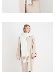Detail shot of a cream white cashmere-like scarf showing thick fringe and soft texture