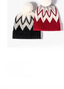 Detailed view of dual-tone wave pattern knit beanie with fluffy faux fur pompom decoration