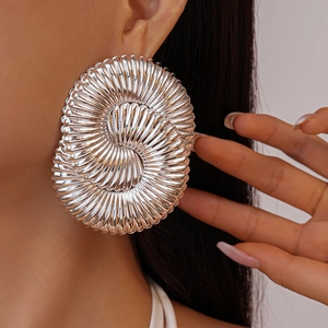 Gros plan sur de grandes boucles d'oreilles argentées à texture spirale et fini métallique