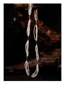 Detail of elegant multi-layer cream pearl necklace draped over a vintage wooden stand