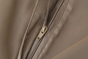 Close-up of high-quality metal zipper detail on khaki wide-leg trousers with satin texture
