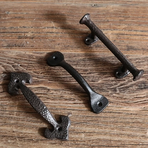 Three vintage cast iron pull handles displayed on aged wood for furniture and doors