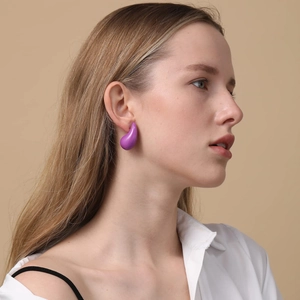 Close-up of a purple teardrop enamel earring on model's ear with vintage aesthetic