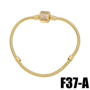 Detail of gold snake chain bracelet featuring a barrel clasp paved with clear zircons