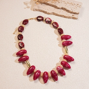 Detailed view of burgundy marble resin beads with gold accents on a beaded necklace