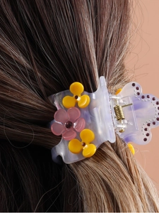 Detail of floral acetate hair claw clip with pink flowers and crystals on dark hair