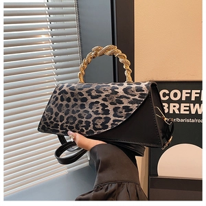 Detail of leopard print handbag with golden twist metal handle and black leather base